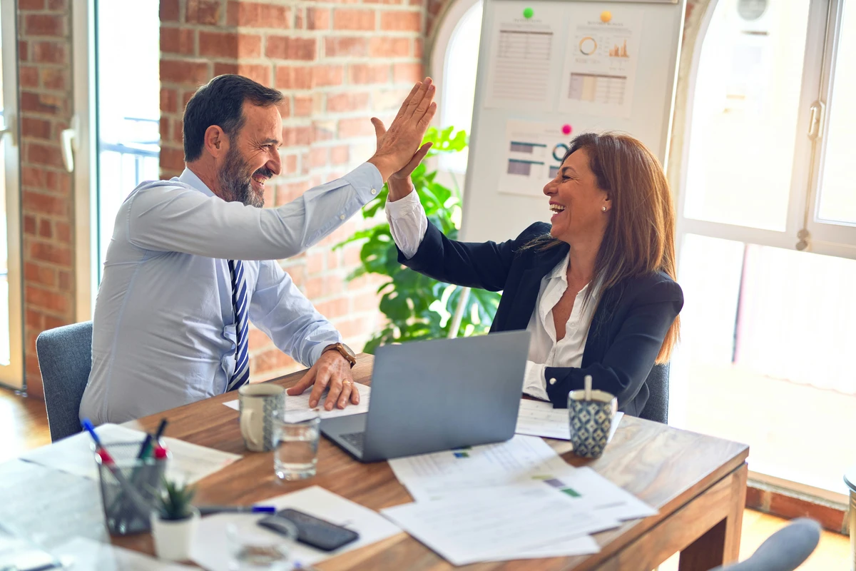 A meeting between two business people, giving each other a high five and smiling